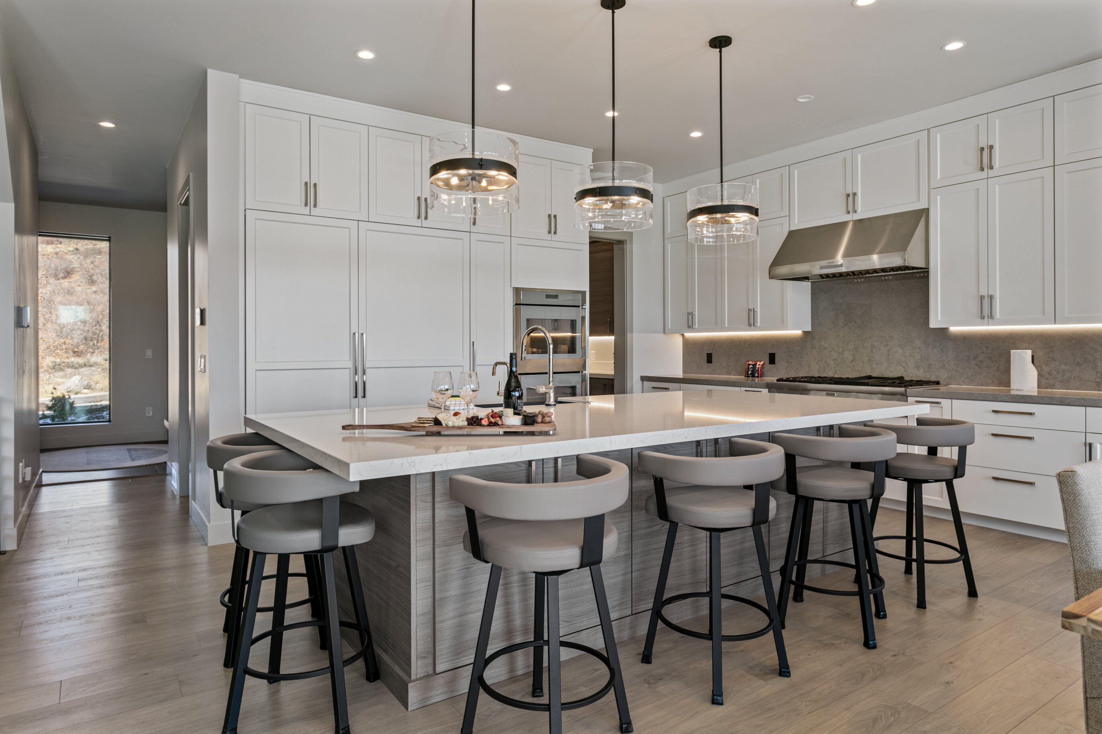 A modern kitchen with a large island, bar stools, and pendant lighting.