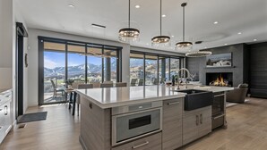 Una cucina moderna con una grande isola, elettrodomestici in acciaio inossidabile e vista sulle montagne attraverso ampie finestre.