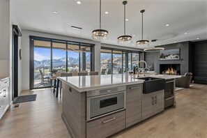 A modern kitchen with a large island, stainless steel appliances, and a view of mountains through large windows. - Spacious Ski Getaway Hot Tub 5 Bedroom 5 Home (Heber City)