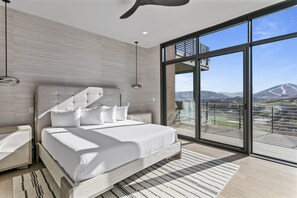 Ein modernes Schlafzimmer mit einem großen Bett, Blick ins Freie und einem Balkon.