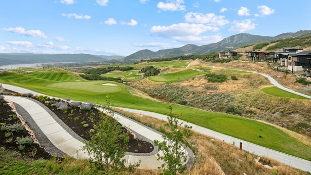 Un campo da golf con un percorso sinuoso e una vista su un paesaggio montano sullo sfondo.