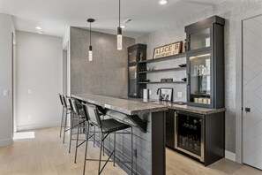 A modern kitchen with a bar area, bar stools, and a wine fridge. - Spacious Ski Getaway Hot Tub 5 Bedroom 5 Home (Heber City)