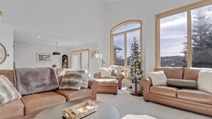 Ein geräumiges Wohnzimmer mit Ledersofas, einem Couchtisch und einem Weihnachtsbaum.