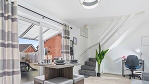 A modern living room with a dining area, a staircase, and a view of the outside. - Telford Centre House with Parking, Garden, Wi-Fi (Telford)