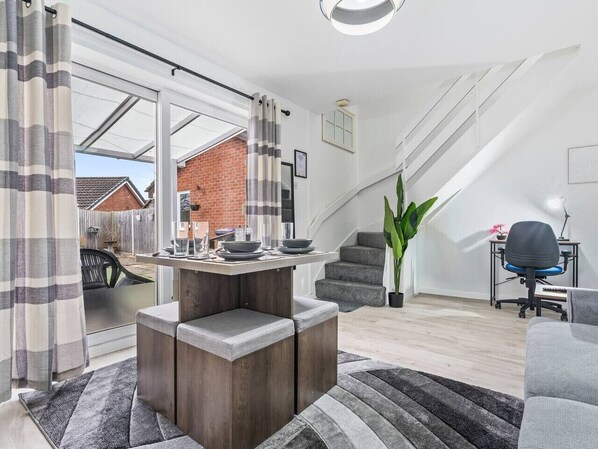 Ein modernes Wohnzimmer mit Essbereich, einer Treppe und Blick ins Freie.