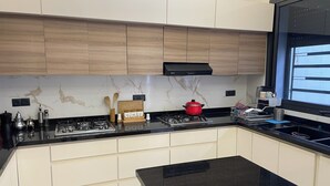 A modern kitchen with a black countertop, wooden cabinets, a red pot on the stove, and a window with blinds. - Beautiful 5-bedroom villa with AC in serene Fes neighborhood (Fes)