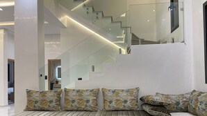 A modern living room with a sofa set, a glass staircase, and a minimalist design. - Beautiful 5-bedroom villa with AC in serene Fes neighborhood (Fes)