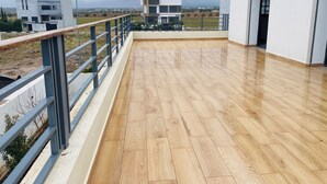 A spacious rooftop terrace with a wooden floor, metal railing, and a view of surrounding buildings. - Beautiful 5-bedroom villa with AC in serene Fes neighborhood (Fes)