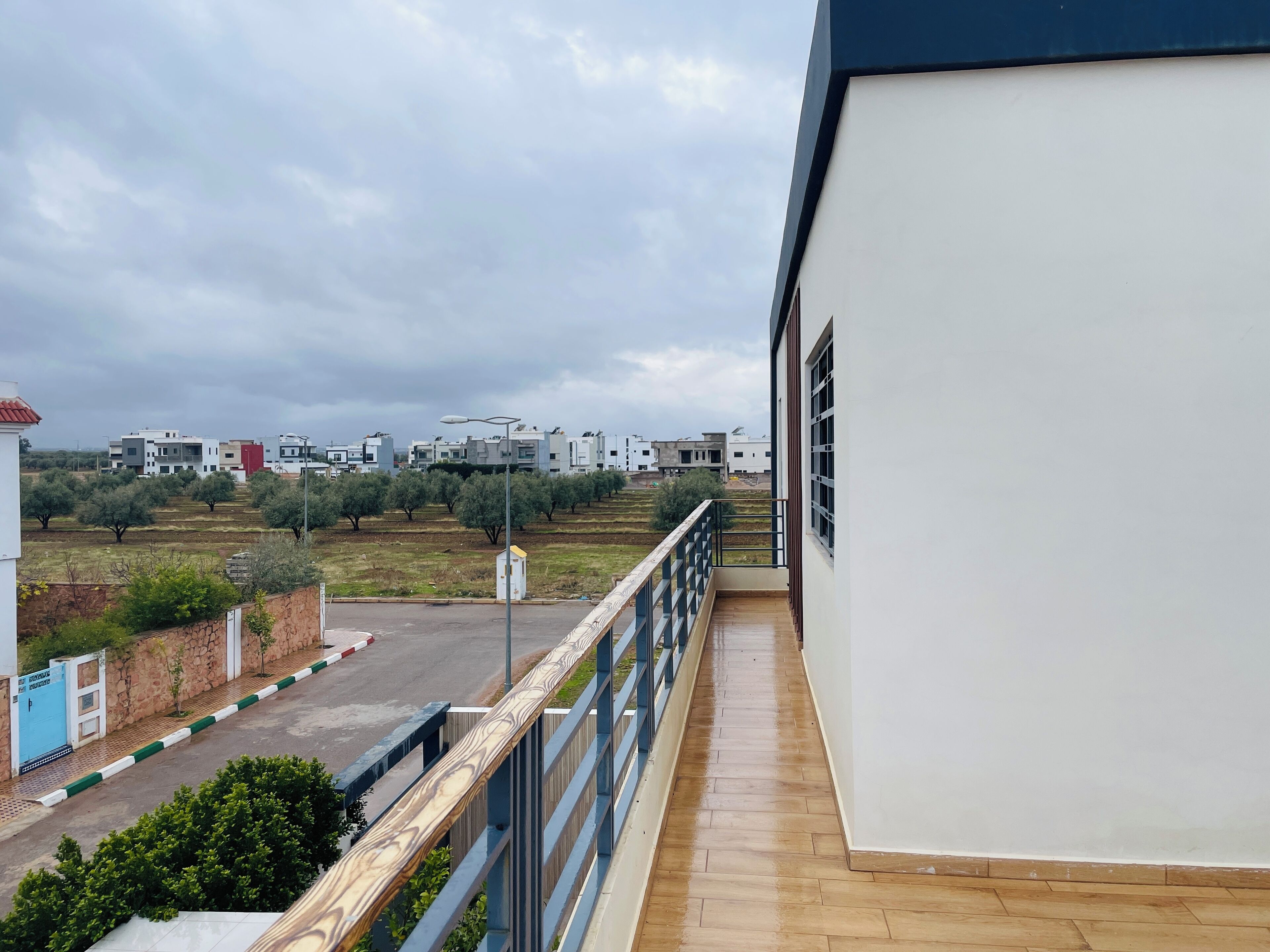 Un balcon avec vue sur des immeubles modernes et un espace de stationnement.