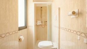 Un baño con ducha, inodoro y toallero.