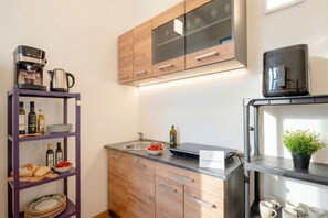 A modern kitchen with wooden cabinets, a built-in oven, a coffee machine, and a shelf with kitchenware. - Welcome to your home away from home! (Bari)