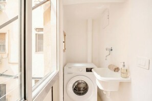 A compact laundry room with a washing machine, a sink, and a towel rack. - Welcome to your home away from home! (Bari)