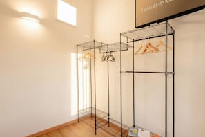 A room with a metal wire shelf unit with wooden hangers and a light fixture. - Welcome to your home away from home! (Bari)