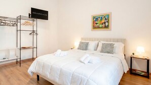 Una habitación de hotel con una cama, un armario, un televisor y un cuadro en la pared.