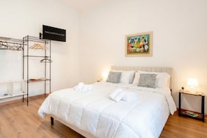 Une chambre d’hôtel avec un lit, une armoire, une télévision et un tableau au mur.