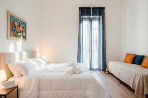 Une chambre d’hôtel avec un lit, une table de chevet, une lampe, une fenêtre avec des rideaux et un tableau au mur.