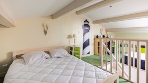 Una camera da letto con un letto, un comodino, una lampada, un punto luce a parete, una scala e vista sul balcone.
