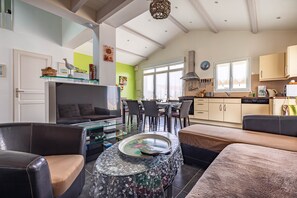 A modern living room with a glass coffee table, leather sofas, and a dining area with chairs and a table. - Pleasant Holiday Home with Private Terrace and Garden (Le Château-d'Oléron)