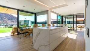 Una cucina moderna con isola in marmo, ampie finestre e vista sull'esterno.