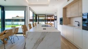 Una cucina moderna con isola in marmo, mobili in legno e zona pranzo con sedie in vimini.