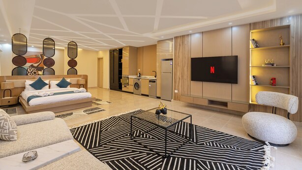 Een moderne woonkamer met een bank, salontafel, televisie en een keukenhoek.