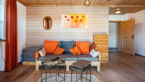 A wooden-paneled room with a sofa, two tables, a mirror, and a painting on the wall. - Apartment 'Gassner' with Balcony and Wi-Fi (Fridolfing)