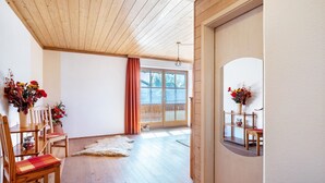 A room with wooden flooring, a wooden ceiling, a large window with curtains, and a door with a mirror. - Apartment 'Gassner' with Balcony and Wi-Fi (Fridolfing)