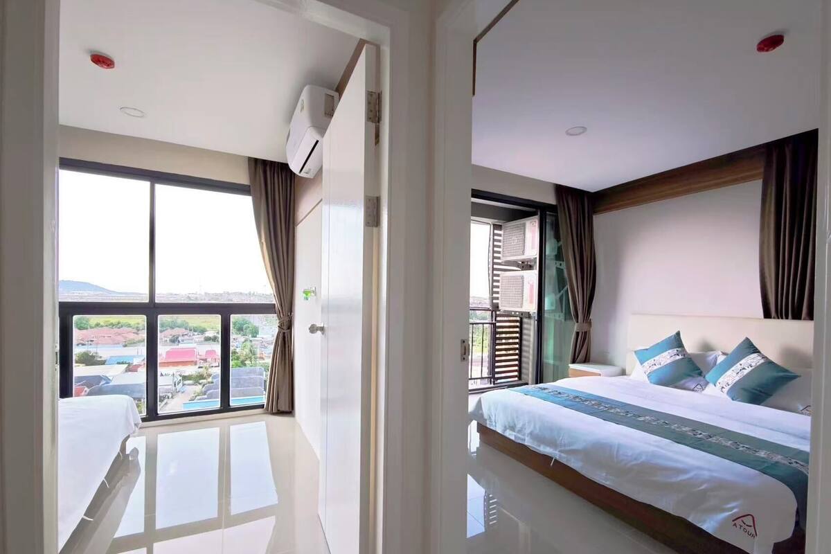 A hotel room with a bed, a window with curtains, and a view of the outside.