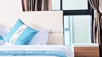 Een hotelkamer met een bed, nachtkastje en een raam met gordijnen.