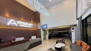 A hotel reception area with a modern design, featuring a reception desk, seating area, and a television screen displaying the hotel's name. - ATOUR Rayong Hotel (Pluak Daeng)