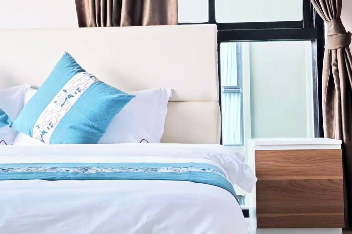 A hotel room with a bed, a nightstand, and a window with curtains.