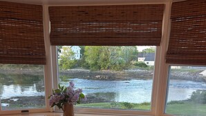 A room with a view of a river, a small table with a woven seat, and two chairs. - Stunning 3-bedroom Weskeag Village River House in South Thomaston (South Thomaston)