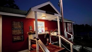 A small, red building with a porch and steps, featuring a signboard with a menu. - Stunning 3-bedroom Weskeag Village River House in South Thomaston (South Thomaston)