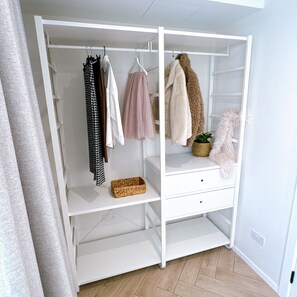 A white wardrobe with hanging clothes, a pink tulle skirt, a fluffy coat, and a wicker basket. - Contemporary Designer Apartment | Exclusive Central Mellieha Stay (Mellieħa)