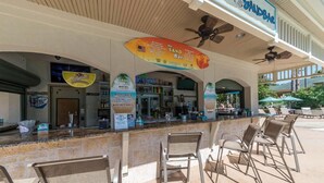 Ett utomhusområde med bar, där det finns en bardisk, stolar och en skylt med texten ”The Sand Bar”.