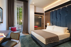 Ein modernes Hotelzimmer mit einem großen Bett, einem Schreibtisch mit Stuhl, einem kleinen Tisch und einem Kleiderschrank.