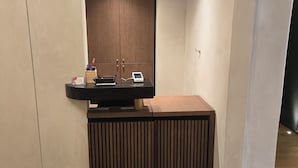 Ein Empfangsschalter mit Holzoptik, ein Telefon und ein kleiner Tisch mit Gegenständen.