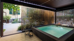 Ein Wellnessbereich mit Whirlpool, Holzterrasse und Bambus-Sichtschutzwänden.