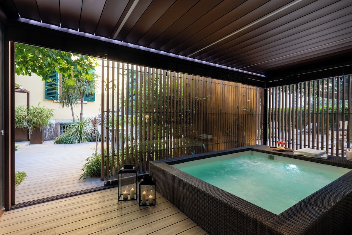 Een wellnessruimte met een jacuzzi, een houten terras en bamboe privacy schermen.
