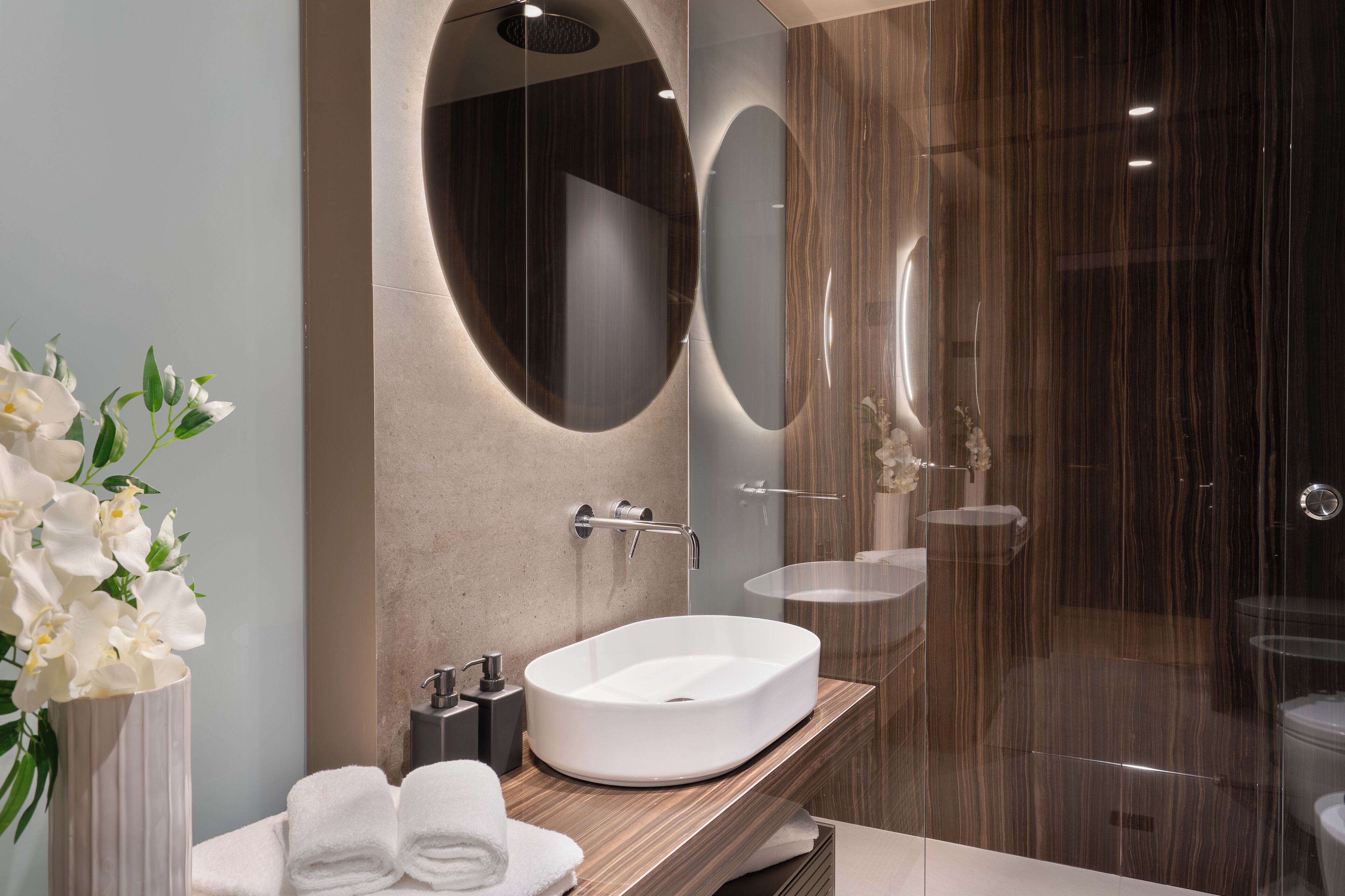 A modern bathroom with a large oval sink, a mirror, and a glass shower enclosure.