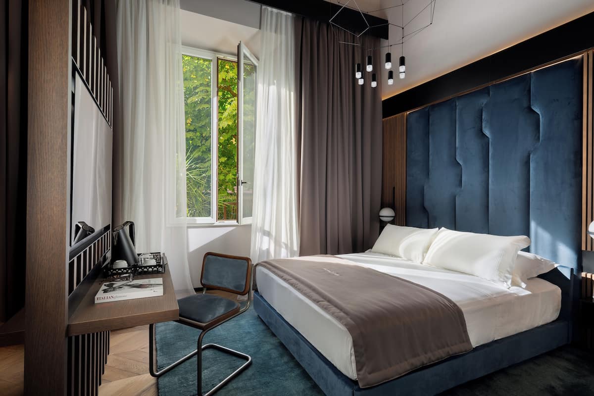 Een moderne slaapkamer met een groot bed, een bureau met stoel en een raam met gordijnen.