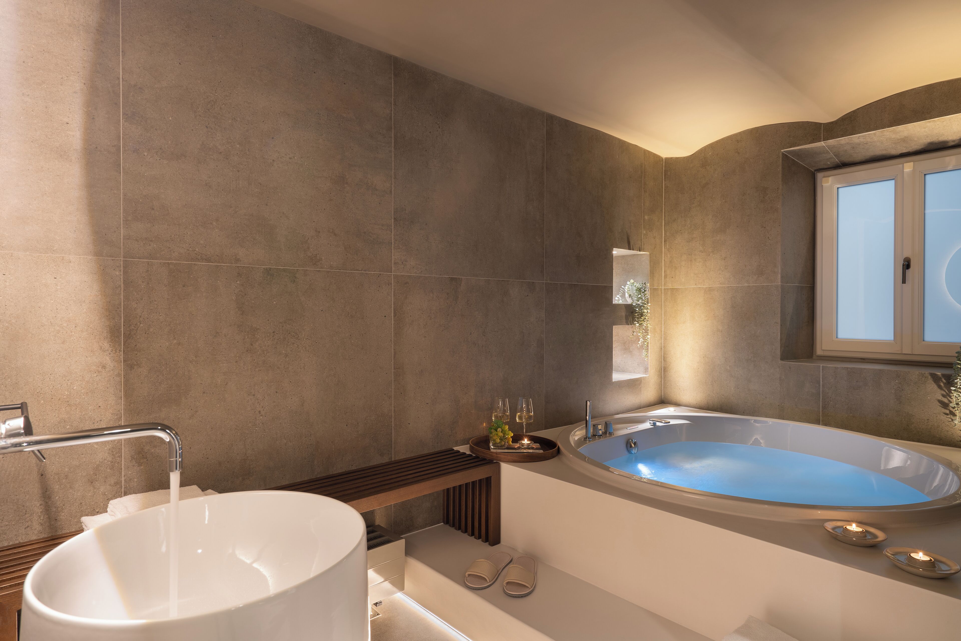 A modern bathroom with a freestanding bathtub, a large sink, and a window.