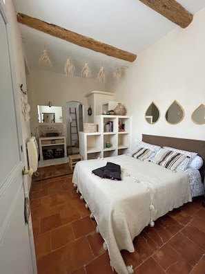 A bedroom with a large bed, a wardrobe, a mirror, and a shelf with books and decorative items. - Charming atypical gîte, canal du midi, near sea, Capestang center (Capestang)