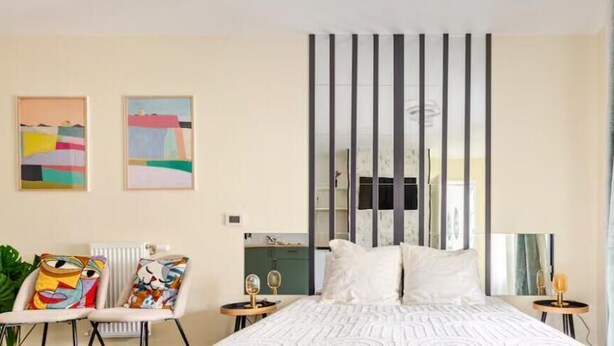 Quarto com cama, cadeira, mesa e duas pinturas na parede.