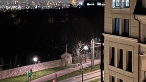 Vista noturna de um horizonte urbano com uma torre iluminada em destaque ao longe.