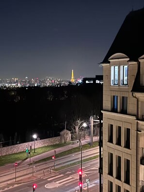 Ein Nachtblick auf eine Stadtlandschaft mit einem markanten, beleuchteten Turm in der Ferne.