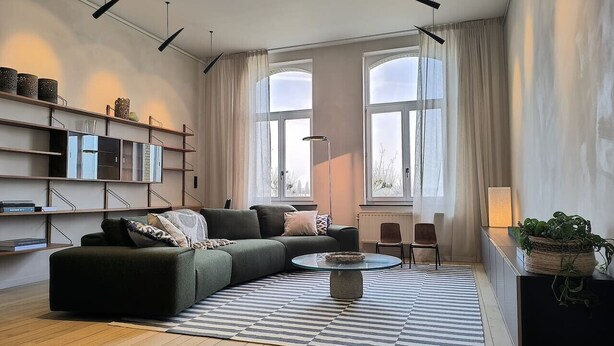 Ein modernes Wohnzimmer mit Ecksofa, Couchtisch und Bücherregal.