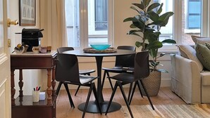 Un coin repas comprenant une table ronde, quatre chaises, une plante en pot et un canapé.