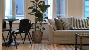 Un salon comprenant un canapé, une table basse, une table à manger avec des chaises et une plante en pot.