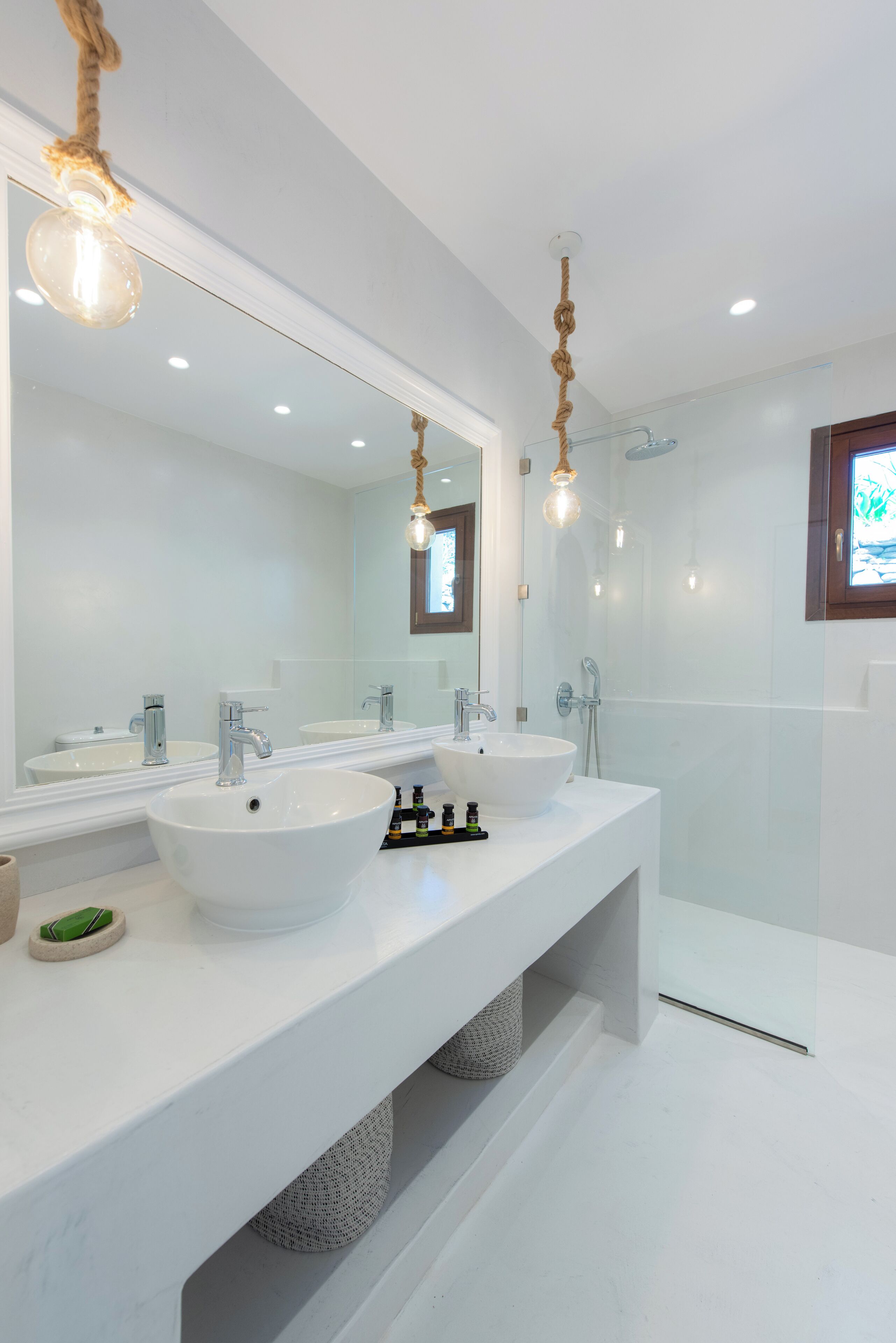A modern bathroom with two sinks, a large mirror, and a glass shower enclosure.